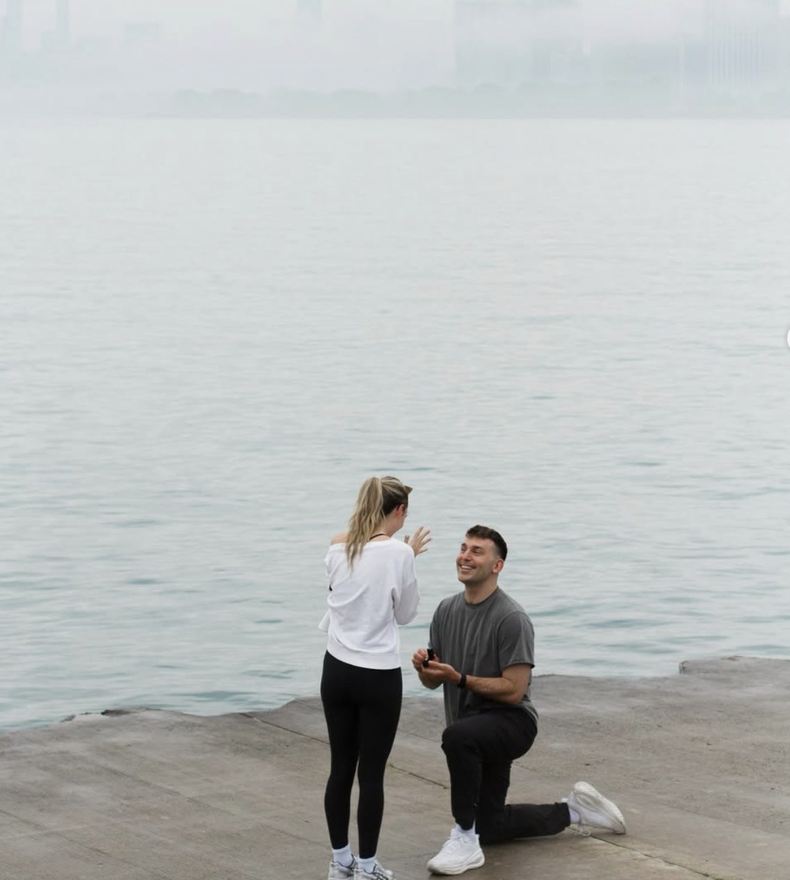 Hirsch down on one knee proposing to Alli on the lakefront